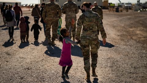 A U.S. military service member hold the hands of an Afghan girl at Holloman Air Force Base in Alamogordo, New Mexico, on November 4, 2021. 