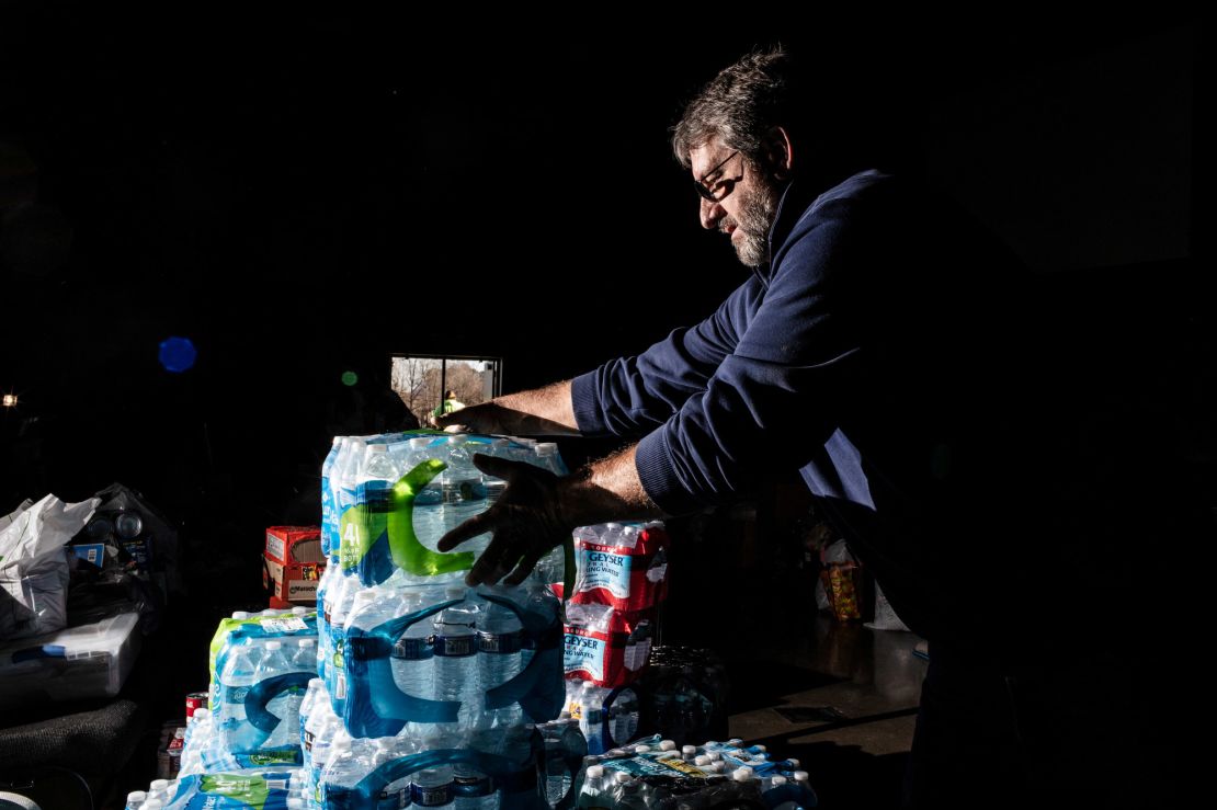 A volunteer carries bottled water to be donated at His House Ministries in Mayfield.