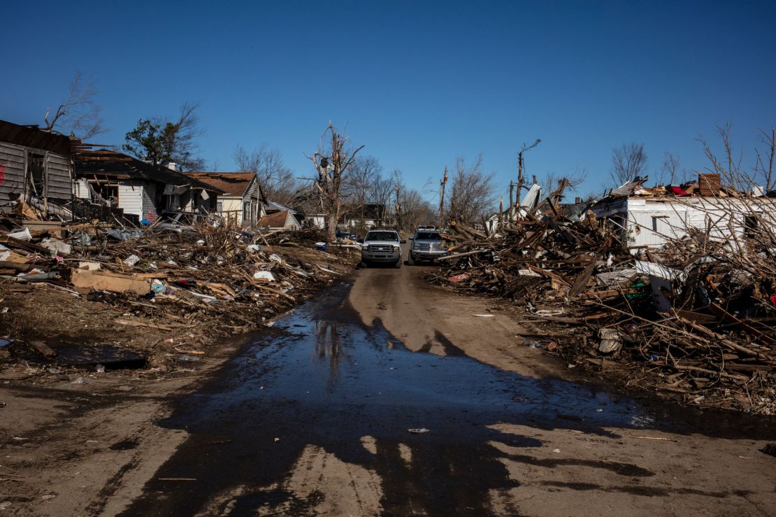 Water from a broken pipe pours into the street from a destroyed home in Dawson Springs.