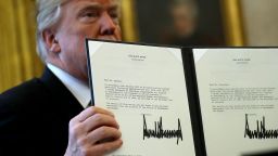 U.S. President Donald Trump holds up a copy of legislation he signed before before signing the tax reform bill into law in the Oval Office December 22, 2017 in Washington, DC.