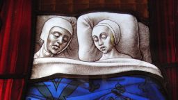 Medieval stained glass church window panel showing a married couple sleeping
