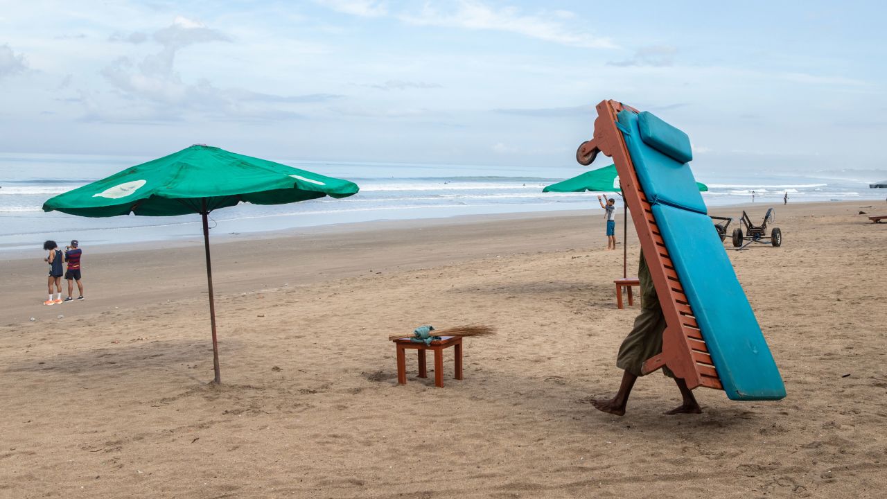 A man carries a lounge chair at the beach in the Kuta area of Bali, Indonesia, on Friday, Oct. 29, 2021. Indonesias President Joko Widodo pushed for travel to reopen in Southeast Asia at the Asean Summit, saying this would help in economic recovery in the region that has seen coronavirus cases recede. Photographer: Putu Sayoga/Bloomberg via Getty Images