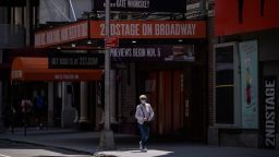 A pedestrian wearing a mask stands walks past a Broadway theatre in New York city on July 30. Multiple broadway shows were forced to cancel shows this week due to Covid-19.