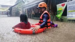 In this handout photo provided by the Philippine Coast Guard, a rescuer assists a girl as they wade through flooding caused by Typhoon Rai in Cagayan de Oro City, southern Philippines on Thursday, Dec. 16, 2021. Tens of thousands of people were being evacuated to safety in the southern and central Philippines as Typhoon Rai approached Thursday at a time when authorities were warning the public to avoid crowds after the first infections caused by the omicron strain of the coronavirus were reported in the country, officials said. (Philippine Coast Guard via AP)