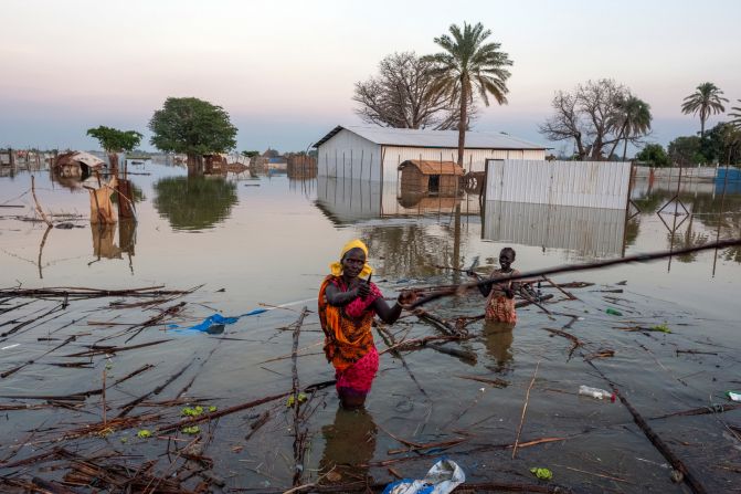 A woman collects driftwood to try to build a shelter for her family.