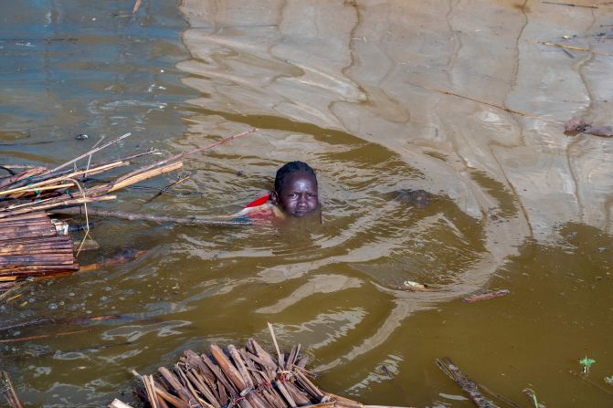 A girl pulls what remains of her family's house through polluted floodwaters.