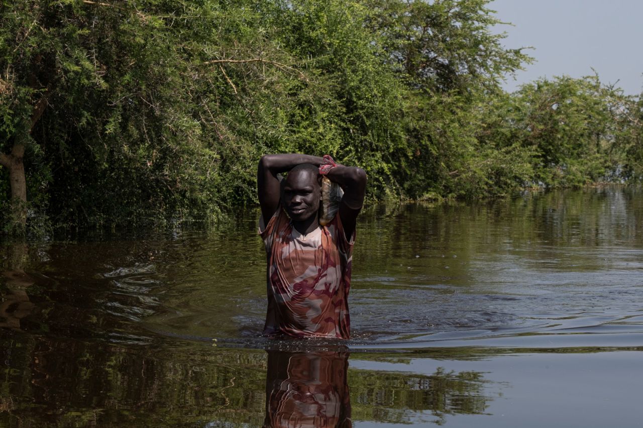 A man carries a sack of grain to his family on higher ground, wading some 10 kilometers (6.2 miles) through floodwaters.