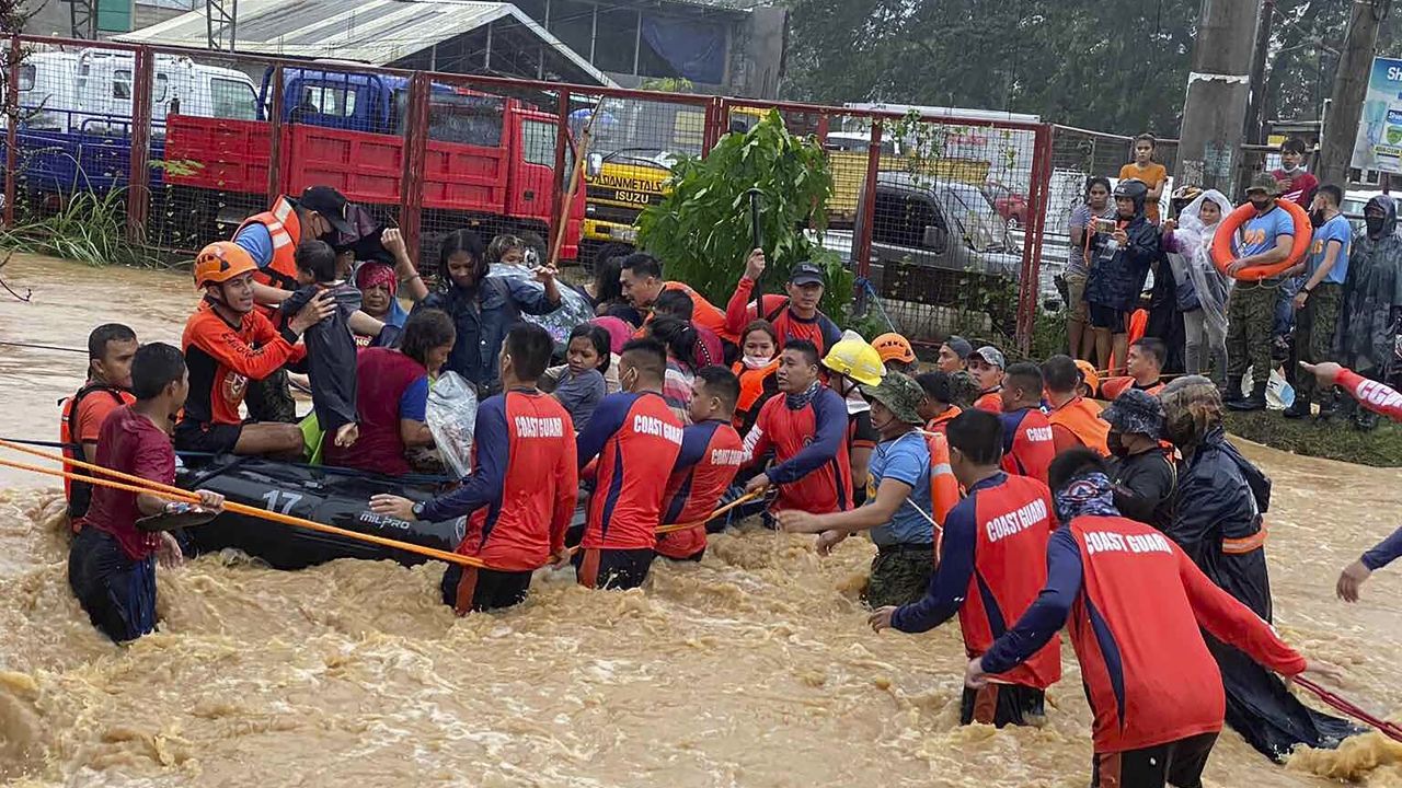 Rescuers help residents over floodwaters caused by Typhoon Rai as they are evacuated to higher ground in Cagayan de Oro City, southern Philippines on December 16, 2021. 