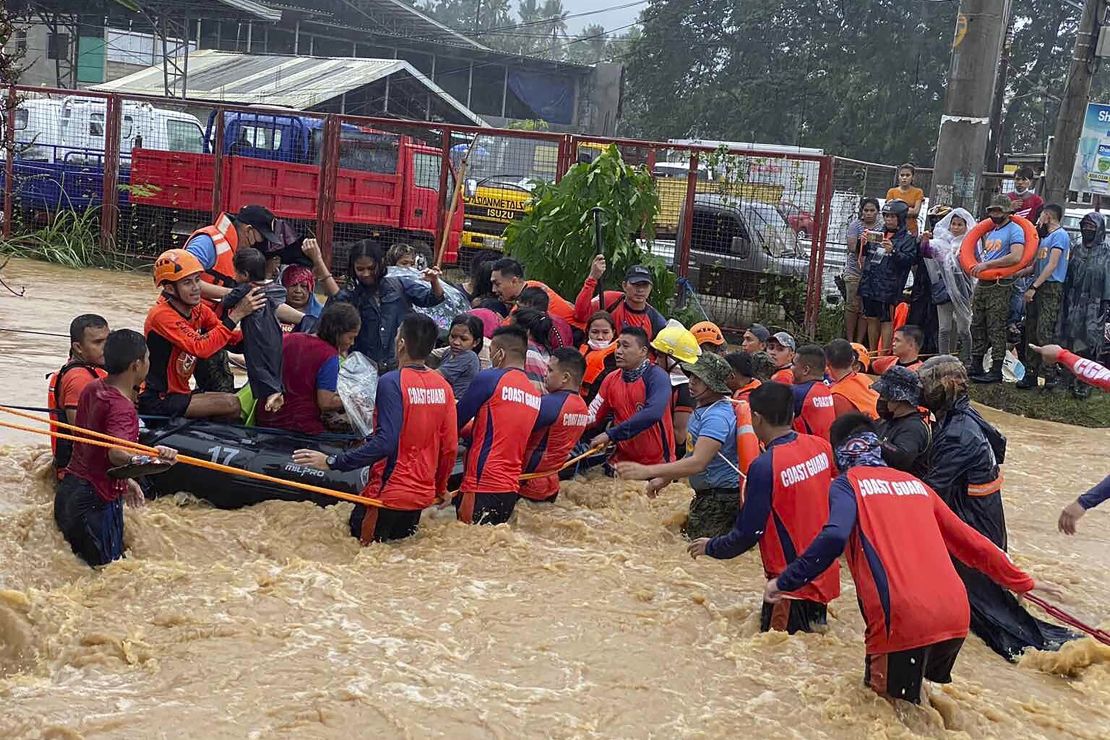 Rescuers help residents over floodwaters caused by Typhoon Rai as they are evacuated to higher ground in Cagayan de Oro City, southern Philippines on December 16, 2021. 