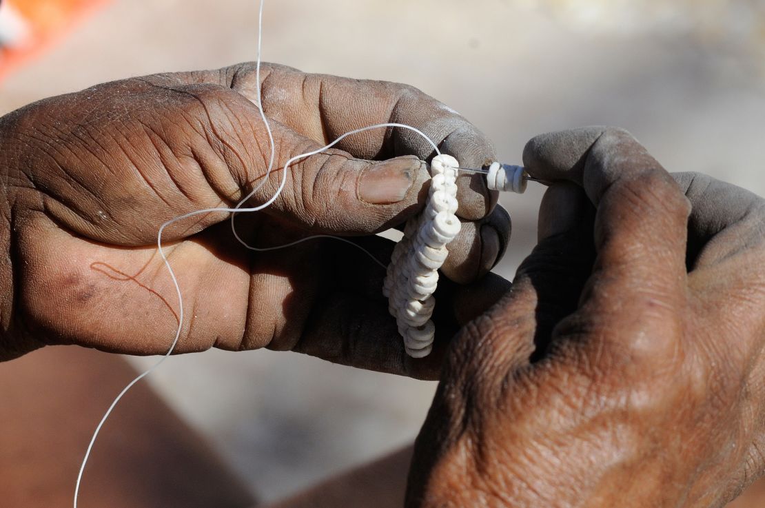 Ostrich eggshell beads being strung together.