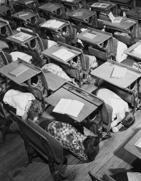 School children learn to protect themselves in case of nuclear attack by practicing a duck-and-cover drill in their classroom in 1951.