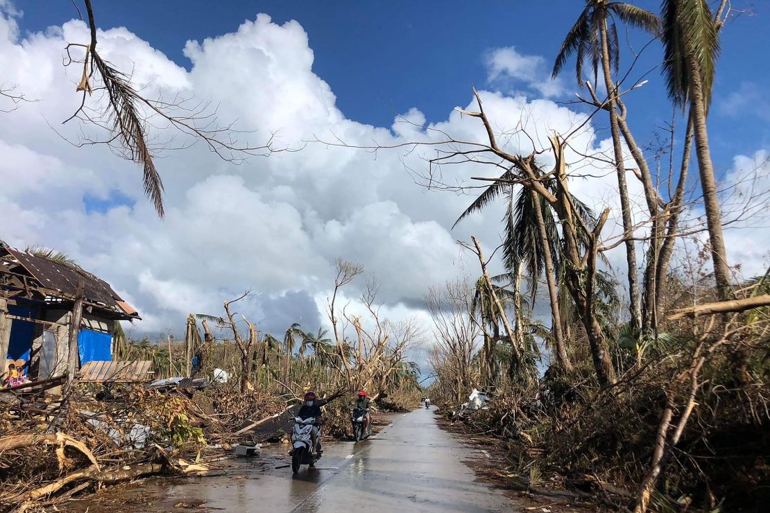 Motorists speed past fallen coconut trees at the height of Super Typhoon Rai along a highway in Del Carmen town, Siargao island on December 20, 2021.