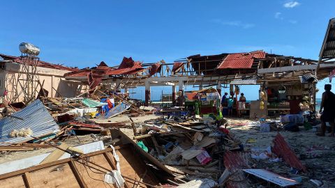 Residents stand next to a destroyed market building in General Luna town, Siargao island, Surigao del Norte province, a day after Typhoon Rai devastated the island.  