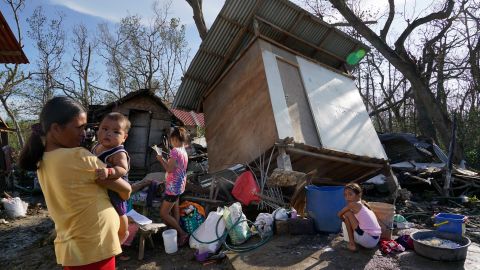 Residents stand in front of damaged homes following Typhoon Rai in Talisay, Cebu province, central Philippines on December 18, 2021. 