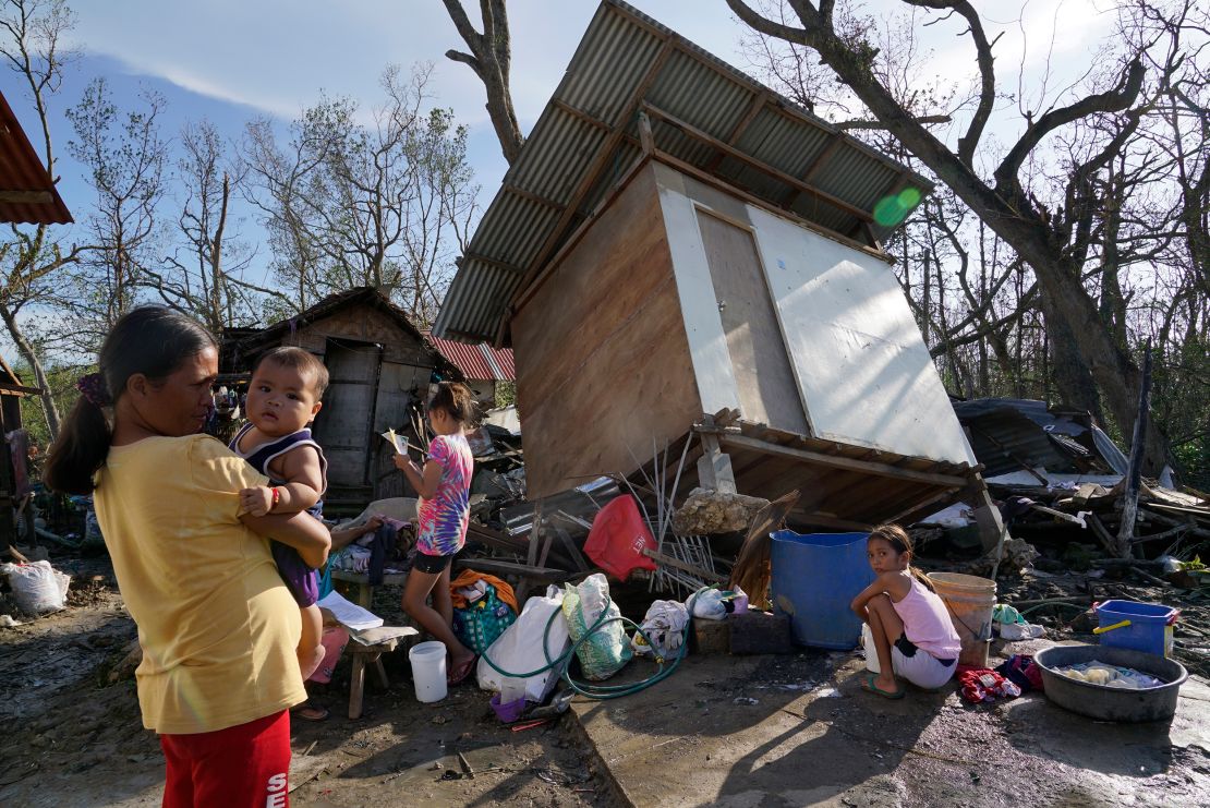 Residents stand in front of damaged homes following Typhoon Rai in Talisay, Cebu province, central Philippines on December 18, 2021. 