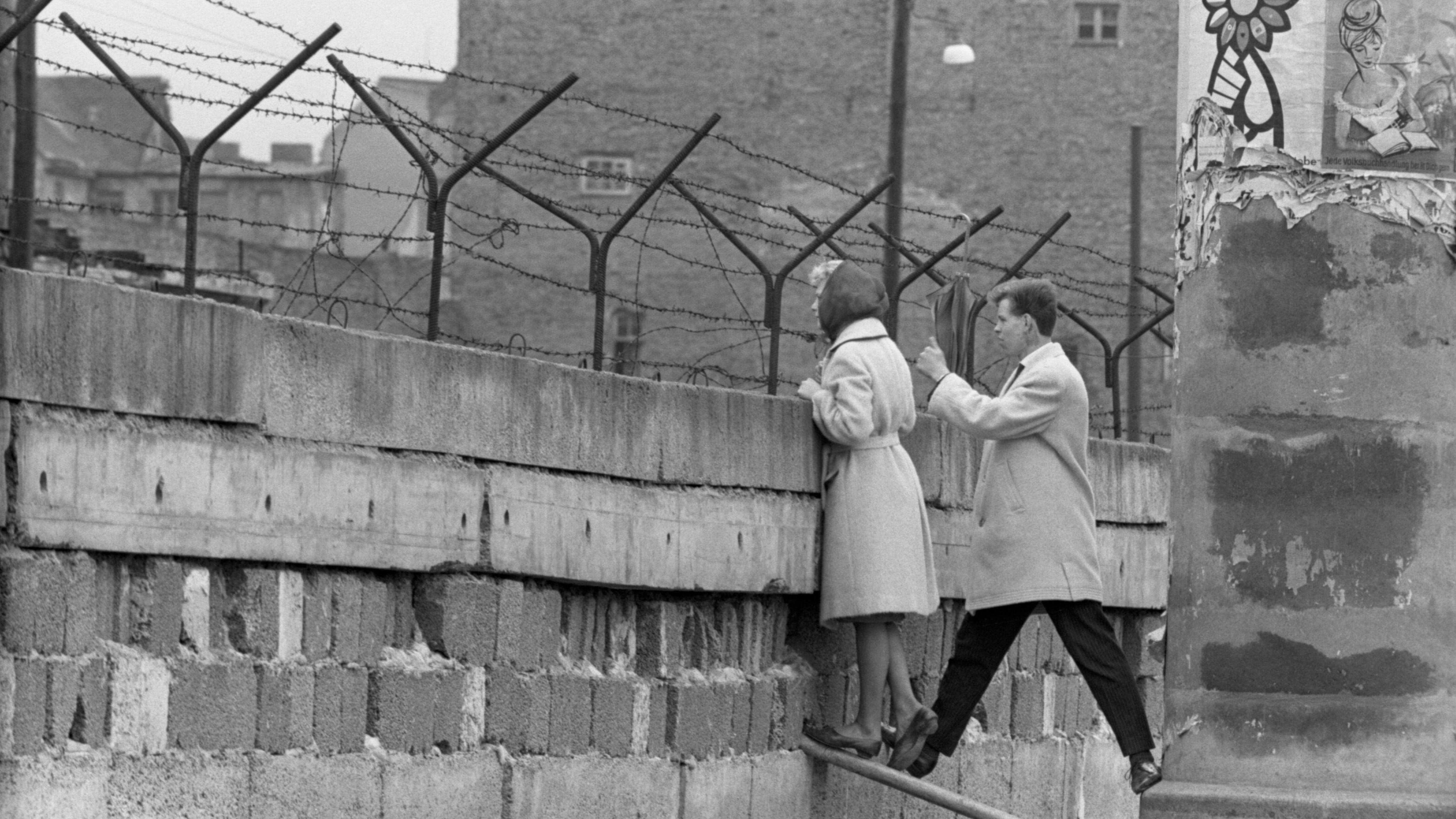 A young woman, accompanied by her boyfriend, stands at the Berlin Wall to talk to her mother on the East Berlin side in 1962. The wall divided the eastern and western sectors of the city. The US had rejected proposals by Soviet leader Nikita Khrushchev to make Berlin a "free city" with access controlled by East Germany, and in August 1961 Communist authorities began construction on the wall to prevent East Germans from fleeing to West Berlin.