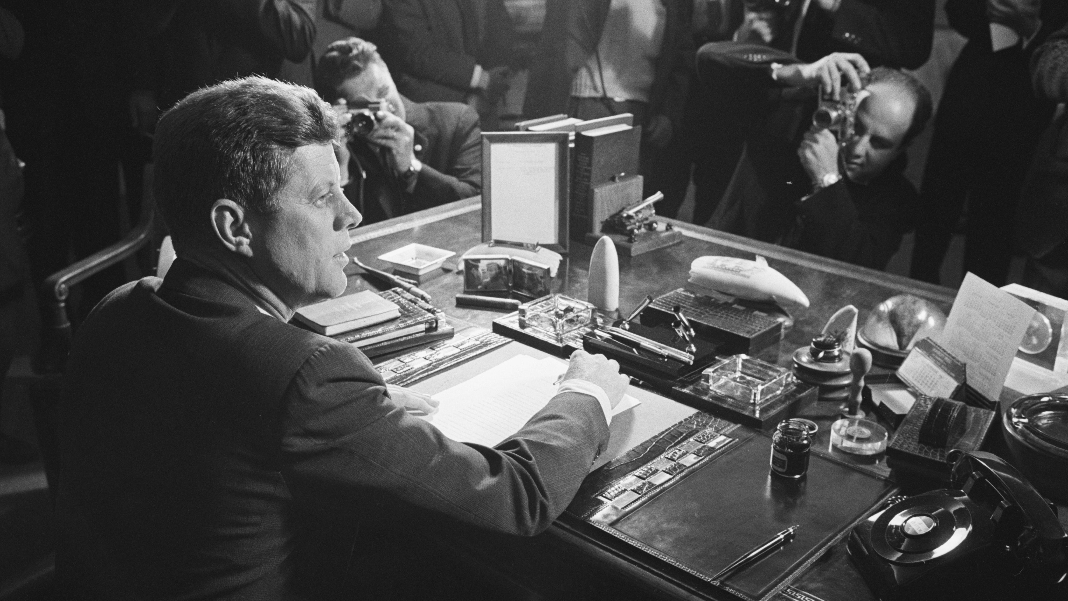 Reporters take pictures of US President John F. Kennedy behind his desk after he signed the arms embargo against Cuba in 1962. The embargo effectively quarantined Cuba. In 1961, a US-organized invasion of 1,400 Cuban exiles was defeated by Castro's forces at the Bay of Pigs. President Kennedy took full responsibility for the disaster. The next year, the Soviet Union installed nuclear missiles on Cuba capable of reaching most of the US. Kennedy ordered a naval blockade of Cuba until the Soviets removed the missiles. Six days later, the Soviets agree to remove the missiles, defusing one of the most dangerous confrontations of the Cold War.