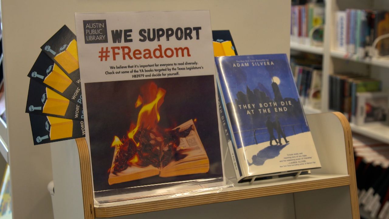 A sign at an Austin Public Library branch encourages readers to check Young Adult books recently targeted by Texas lawmakers. Next to the sign, there is a copy of "They Both Die at the End" by Adam Silvera, whose several other books are being targeted by lawmakers in the state in recent months. 