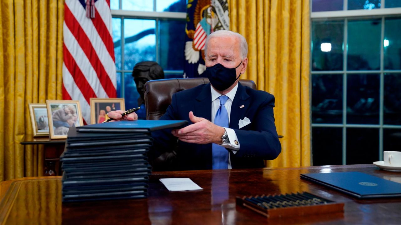 President Joe Biden signs his first executive orders in the Oval Office of the White House on January 20, 2021, in Washington.