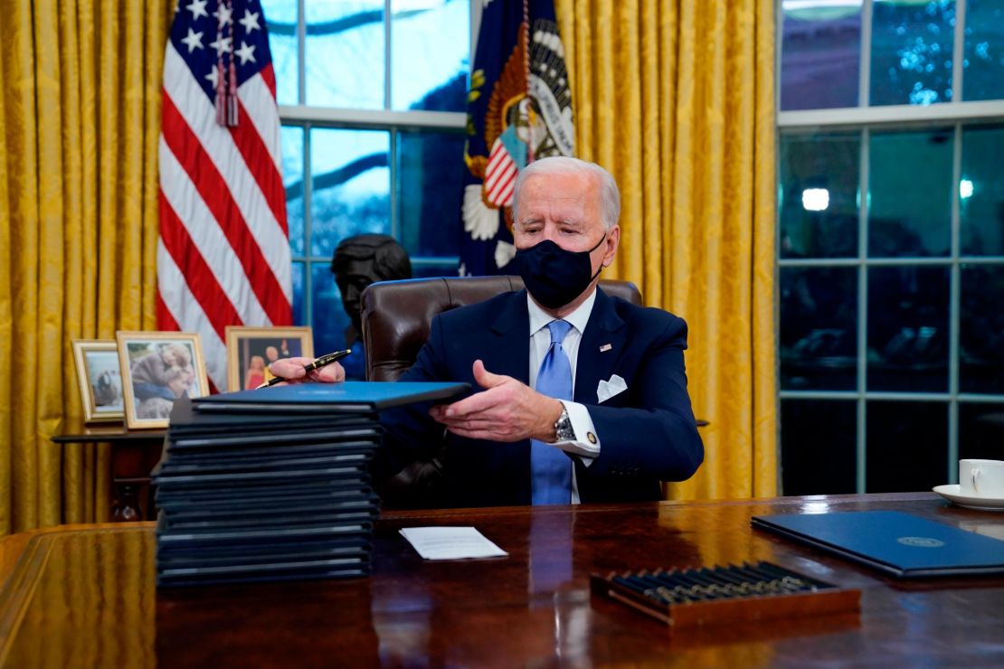 President Joe Biden signs his first executive orders in the Oval Office of the White House on January 20, 2021, in Washington.