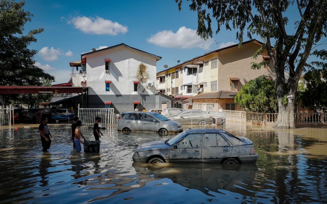 Residents carrying food and daily necessities are seen wading through a road in water during the massive floods in the outskirts of Shah Alam.
