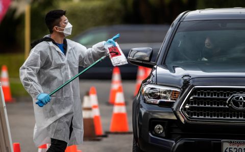 A health-care worker hands out a test kit at a testing site in Riverside, California, on December 21.