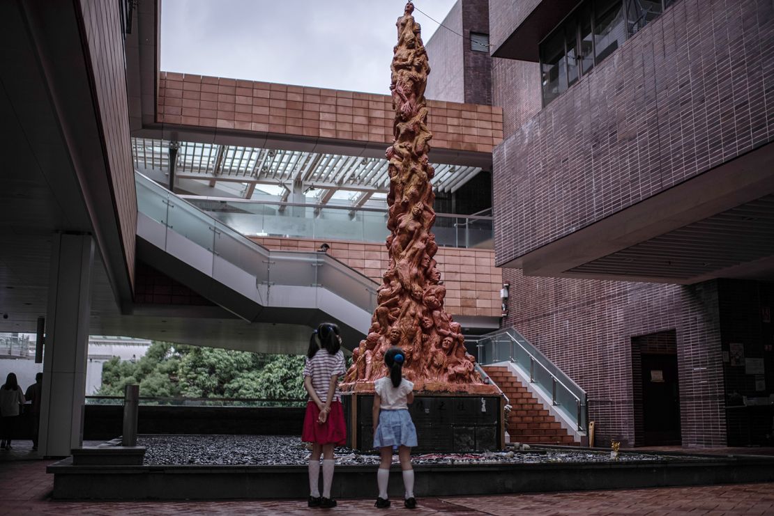 Two children look at the "Pillar of Shame" statue at the Hong Kong University campus on October 15, 2021, in Hong Kong.