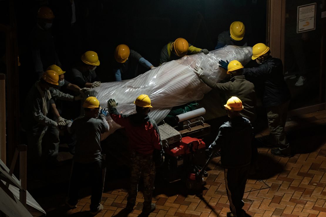 Workers remove part of the "Pillar of Shame" into a container at University of Hong Kong on December 23, 2021 in Hong Kong.