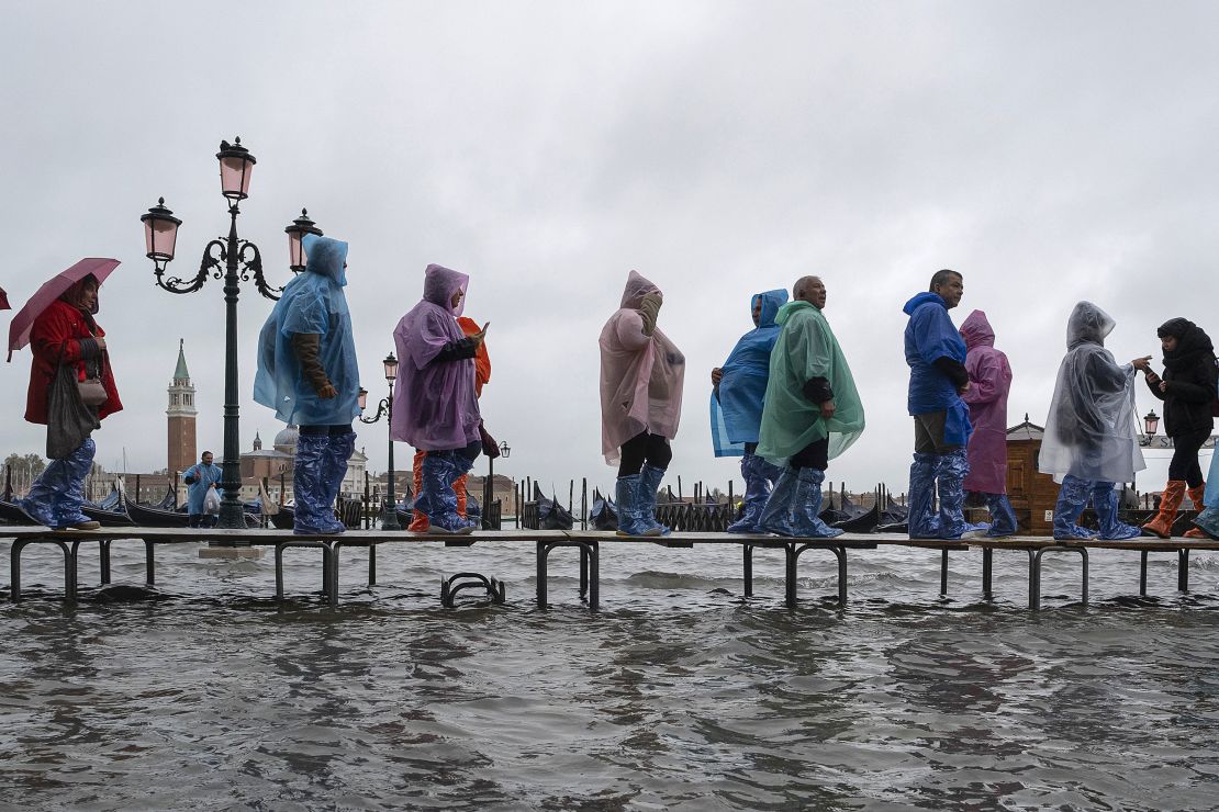 Tourists typically navigate Venice flooding on raised walkways.