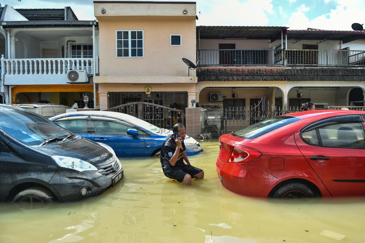 A man talks on the phone while sitting between cars amid floodwaters in Shah Alam, Malaysia, on December 21. <a href="https://www.cnn.com/2021/12/21/asia/malaysia-floods-response-intl-hnk/index.html" target="_blank">Flooding in the country</a> led to more than a dozen deaths and the displacement of over 60,000 people.