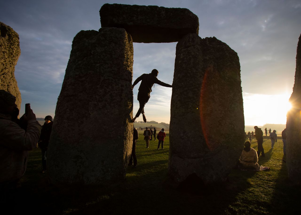 A reveler climbs stones as people gather to celebrate the winter solstice at Stonehenge in Wiltshire, Britain, on December 22. 
