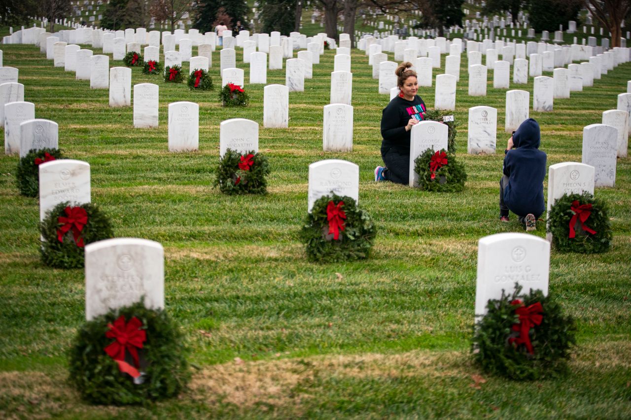 A woman poses for a photograph after placing a wreath on a tombstone at Arlington National Cemetery on December 18. Wreaths were placed on more than 250,000 tombstonoes during the 30th annual "Wreaths Across America" project.