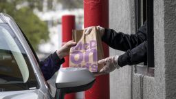 An employee wearing protective gloves hands an order to a customer through a drive-thru window at a McDonald's Corp. restaurant in Oakland, California, U.S., on Thursday, April 9, 2020. 