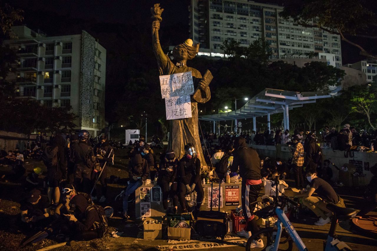 Protesters sit next to a "Goddess of Democracy" statue at the Chinese University of Hong Kong (CUHK) in Hong Kong on November 12, 2019. 