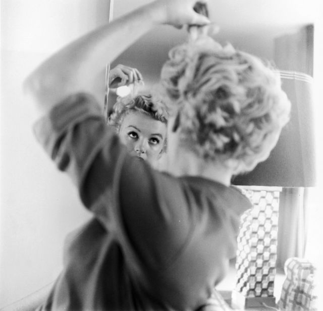 Monroe fixes her hair in front of a mirror in 1951. That year she had several supporting roles in comedies, including 