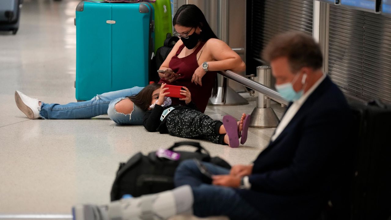 Una mujer y un niño esperan su vuelo junto a otro viajero en el Aeropuerto Internacional de Miami el lunes 27 de diciembre.