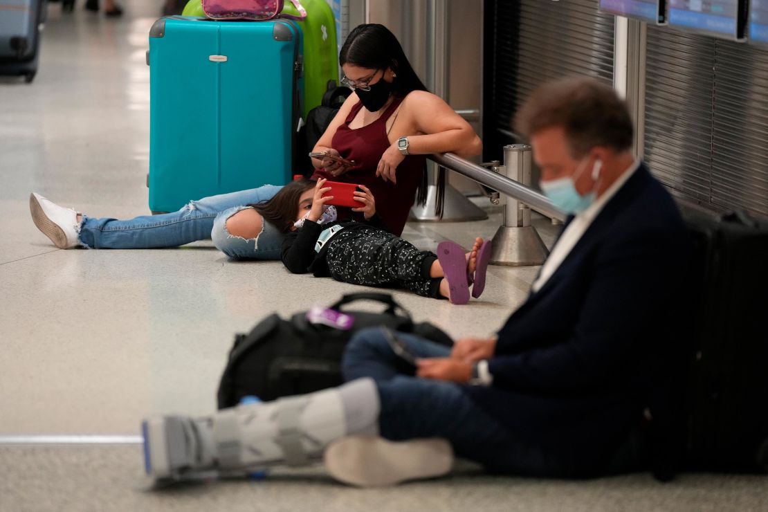 A woman and child wait for their flight alongside another traveler at Miami International Airport on December 27, 2021.