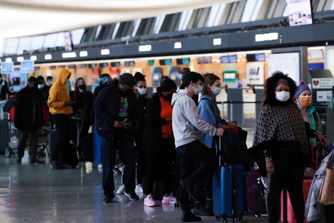 Passengers wait in line to check in for their flights at the Dulles International Airport in Dulles, Virginia, on December 27, 2021. 