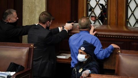Police draw their guns as rioters try to break into the House chamber. "I kept my lens focused on that door and waited for the breach," said Associated Press photographer J. Scott Applewhite, the only journalist in the House chamber at the time. "When the mob began to break the glass in the door, I could barely see the face of one of the rioters. The cops and a new congressman with a law enforcement background tried to de-escalate the situation. Their guns were drawn and pointed at the hole in the glass. The growl of the mob could be heard on the other side."