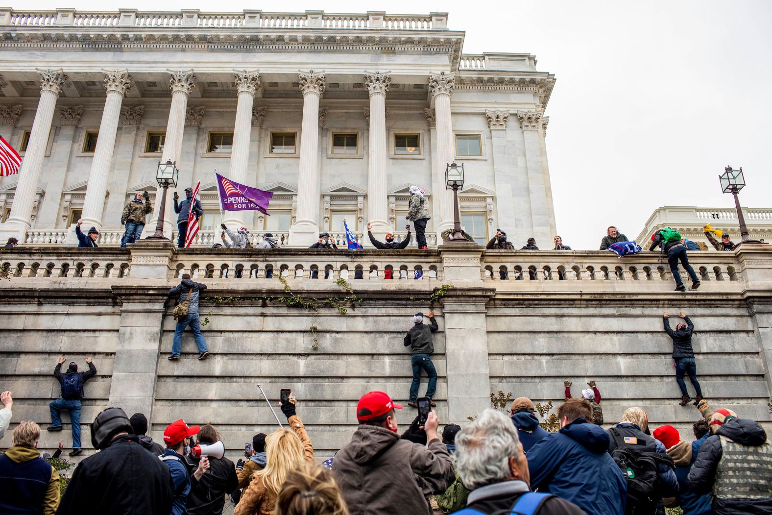 Trump supporters climb a wall outside the Capitol.