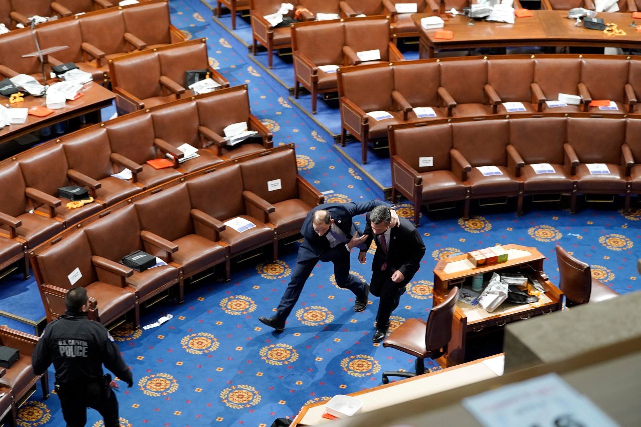Members of Congress run for cover as rioters try to enter the House chamber.