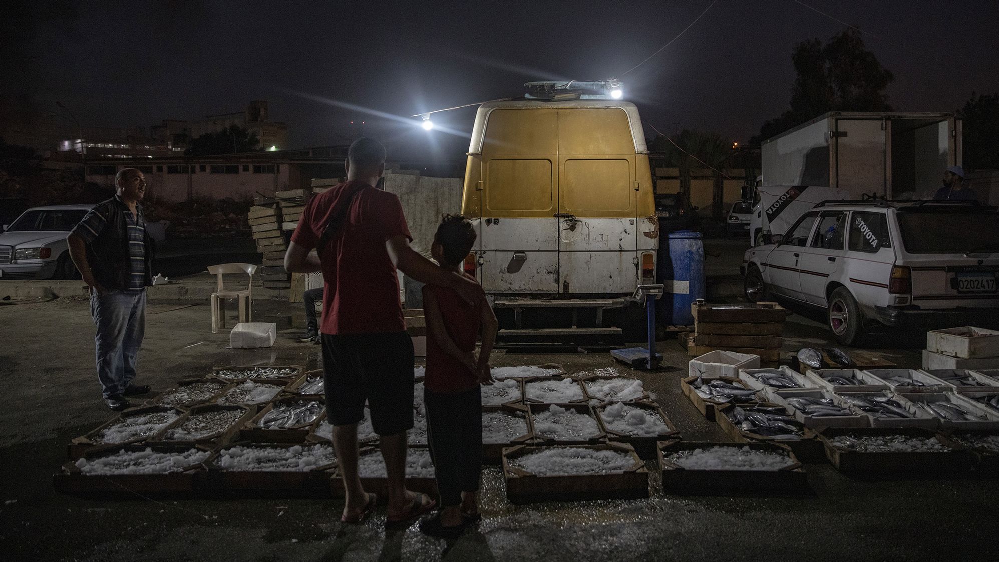 A father and son walk through a fish market lit by power from a generator in Beirut, Lebanon, in September.