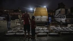 A father and son browse fish at a stall illuminated by a light powered by a private electricity generator at the fish market, in Beirut, Lebanon, on Wednesday, Sept. 8, 2021. Egypt agreed to supply natural-gas to Lebanon through Jordan and Syria as the Arab states seek to help end power shortages in their crisis-ridden neighbor. 