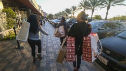 Black Friday shoppers wearing face masks carry bags at the Citadel Outlets in Commerce, Calif., Friday, Nov. 26, 2021.