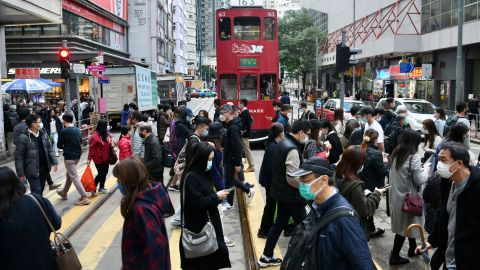 People wearing face masks cross a street in Hong Kong on December 21.
