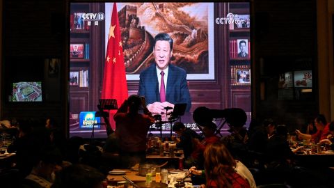 People have their dinner at a restaurant as a screen broadcasts Chinese President Xi Jinping delivering his New Year speech in Beijing on December 31, 2021.