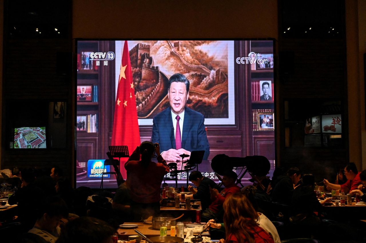 People have dinner at a Beijing restaurant as a screen broadcasts Chinese President Xi Jinping delivering his New Year speech.