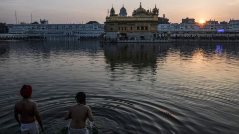 Sikh devotees take a dip in the holy Sarovar (water tank) during the last sunset of 2021 on the eve of New Year 2022, at the Sikh shrine Golden Temple in Amritsar on December 31, 2021.
