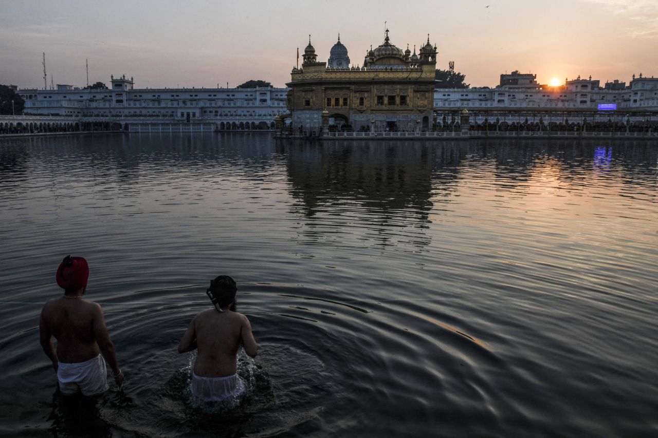 During the last sunset of 2021, Sikh devotees take a dip in the holy Sarovar near the Golden Temple shrine in Amritsar, India.