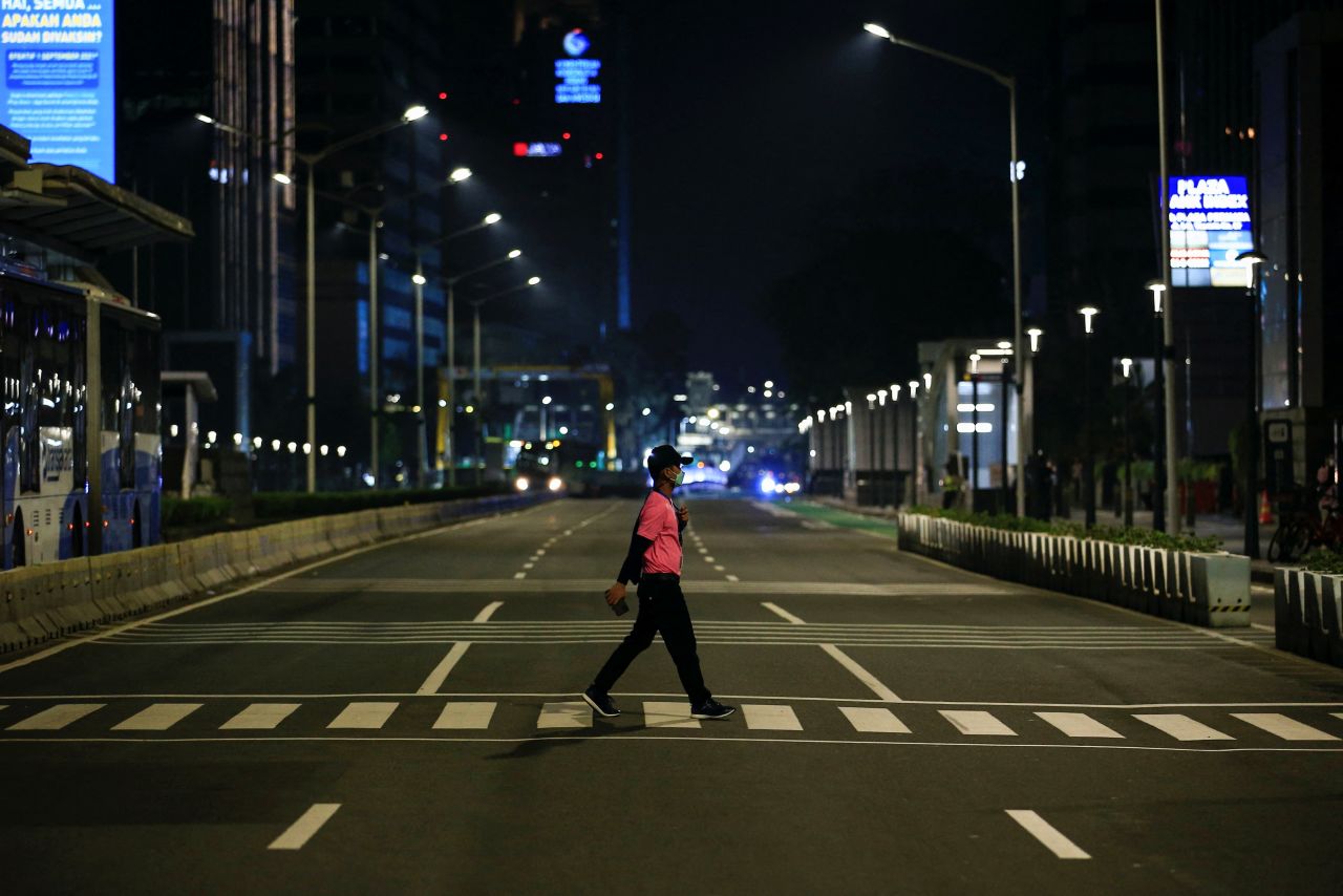 A man crosses an empty road near a Jakarta, Indonesia, roundabout where people usually celebrate New Year's Eve.
